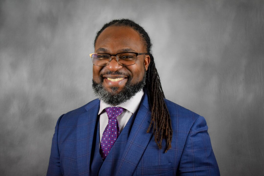 Vernon Green Jr. wearing a blue suit in front of a grey backdrop